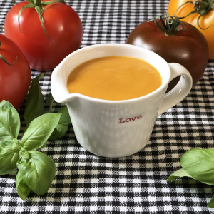 Apricot vinaigrette in a white pitcher surrounded by tomatoes and basil