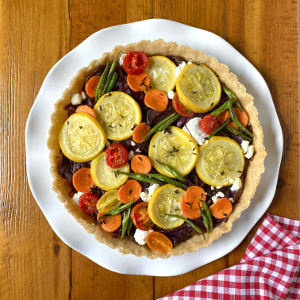 Vegetable tart on white plate with red gingham napkin