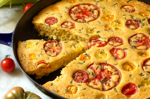 Skillet cornbread topped with tomatoes and rosemary