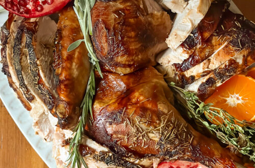 roasted turkey on a platter with pomegranates and herbs
