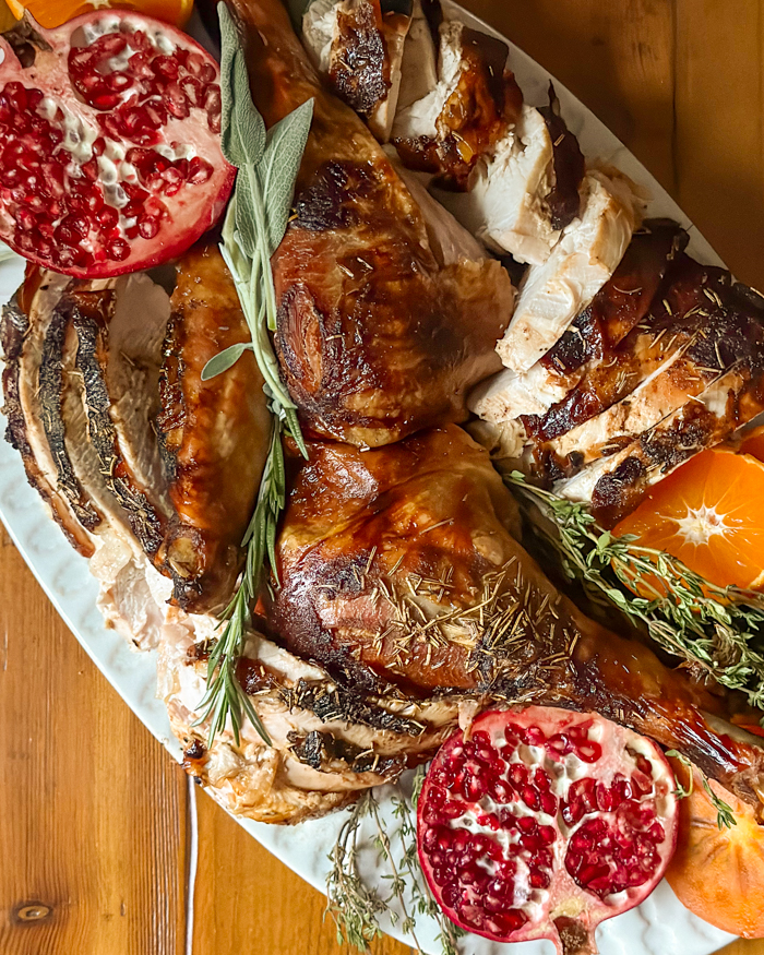 roasted turkey on a platter with pomegranates and herbs