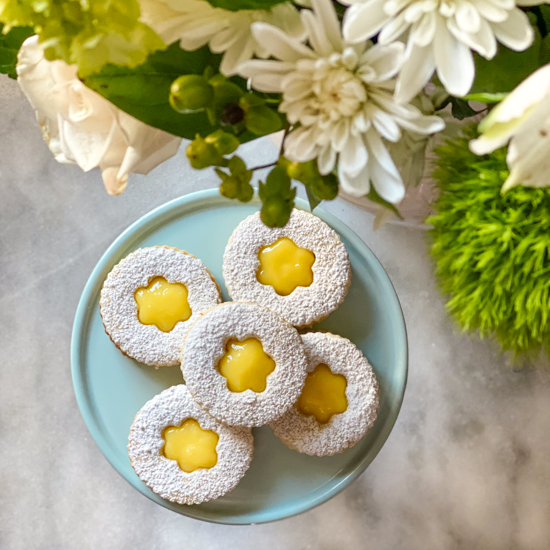 Coconut cookies with lemon curd filling and fresh flowers on a kitchen counter