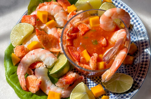 Mango cocktail sauce with shrimp and lobster on a plate with limes and mango pieces