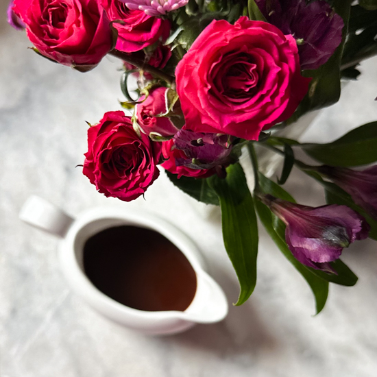 Chocolate balsamic vinaigrette in a white container surrounded by roses