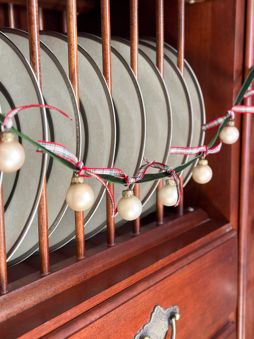 a garland of glass ball ornaments hanging from green velvet ribbon tied with plaid ribbons